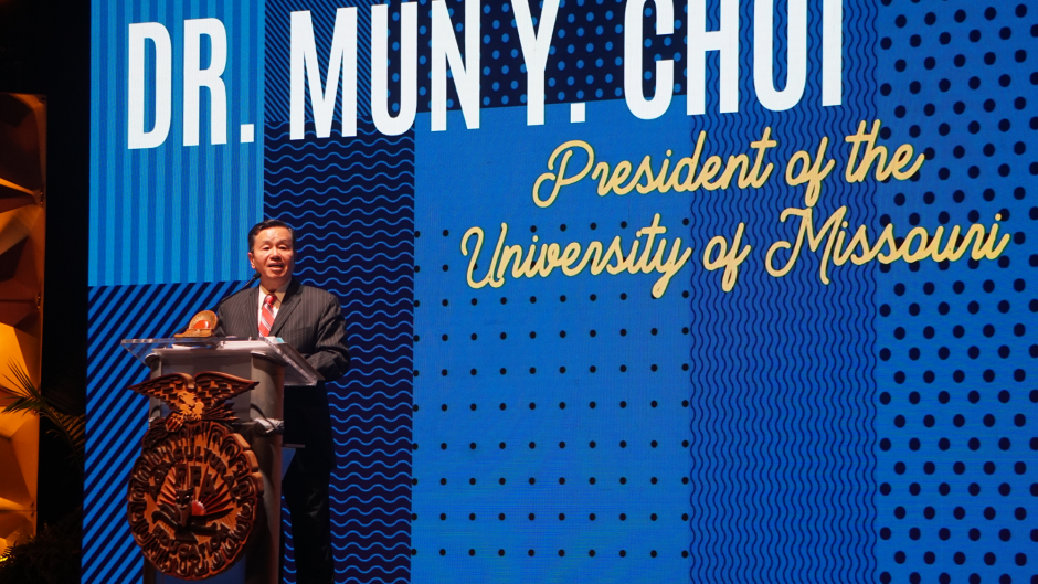 President Mun Choi at podium in front of blue patterned background
