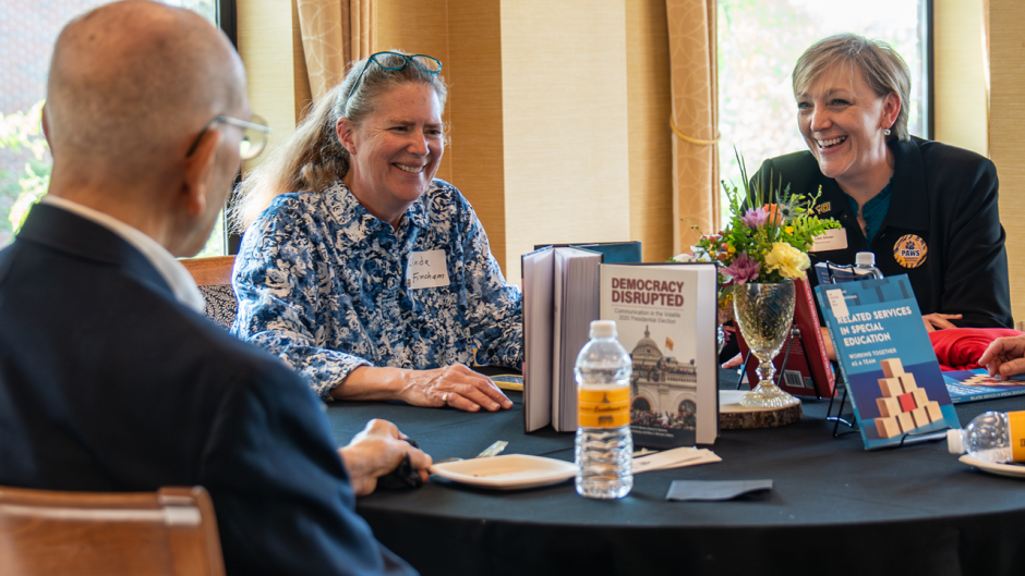 Three people at table talk about books.