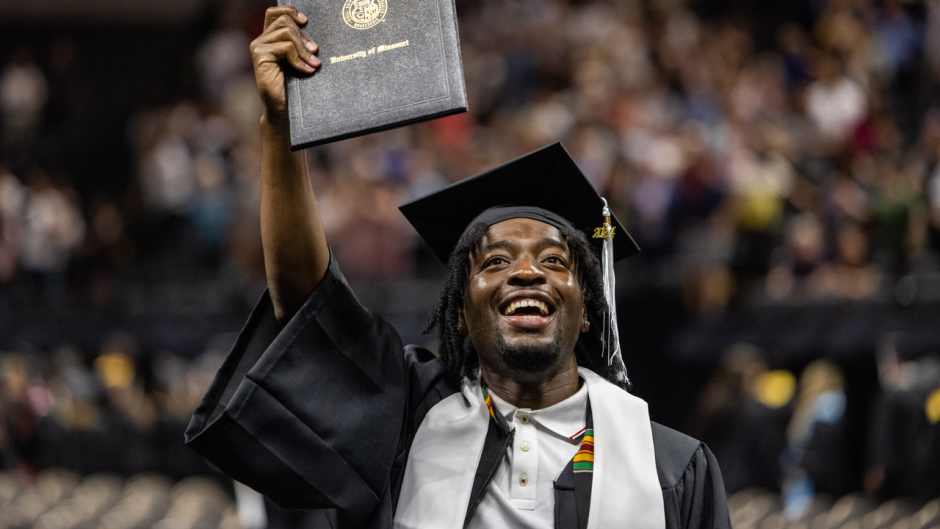 Student raising diploma and smiling